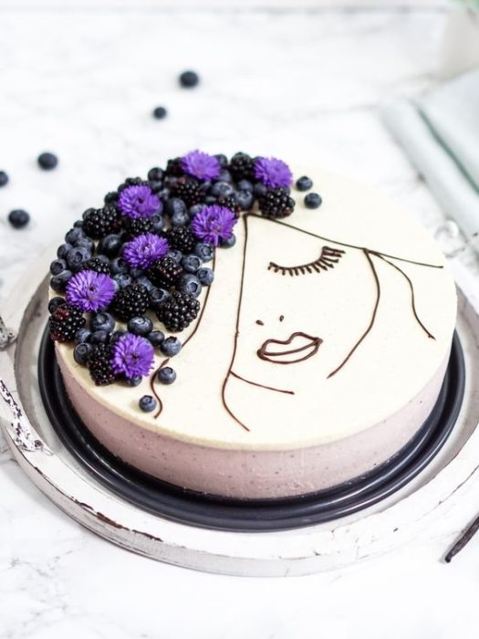 Pastel con cobertura blanca decorado con frutas en forma de cabellera