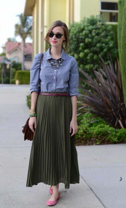 Chica usando maxi falda color verde army con flats rosas, cinturón café, camisa de mezclilla y bolso de mano