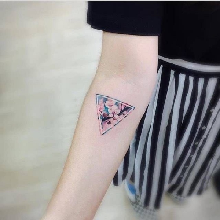 Tatuaje de flores en el antebrazo en forma de un triángulo con margaritas