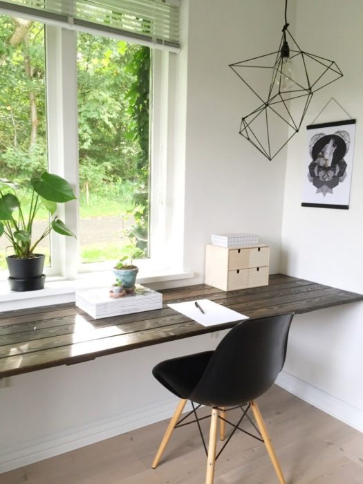 Escritorio con estilo minimalista, sobre una base de madera y silla color negro a juego con tonos blancos