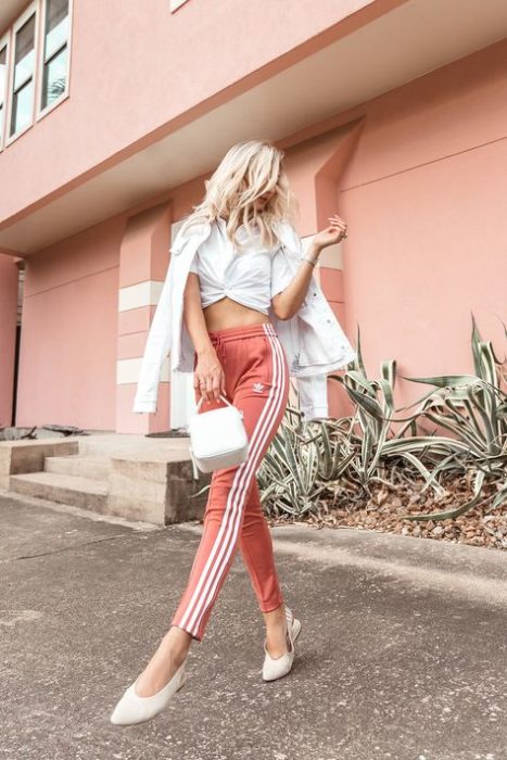 Chica posando con un outfit de pants en color coral con abrigo y blusa blanca