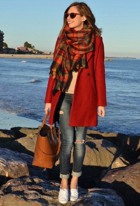 Chica usando bufanda larga de color roja con líneas grises y negras, jeans, y abrigo rojo