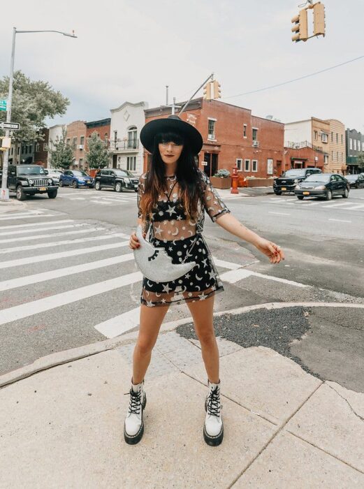 Chica posando para una fotografía mientras usa un vestido plateado con estrellas y botas Dr. Marten blancas con cintas negras