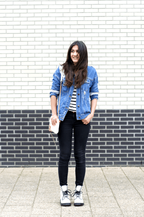 Chica con look casual de jeans negros, chaqueta de mezclilla y blusa a rayas con botas Dr. Martens