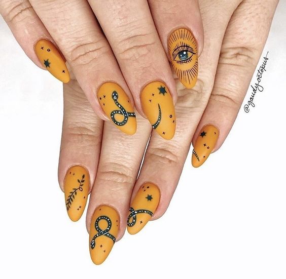 Chica con uñas en tonos mostaza decoradas con serpientes y ojos; Uñas para chicas fascinadas por el ocultismo