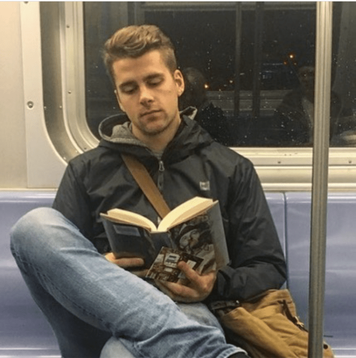 Hombre con chamarra oscura concentrado leyendo un libro