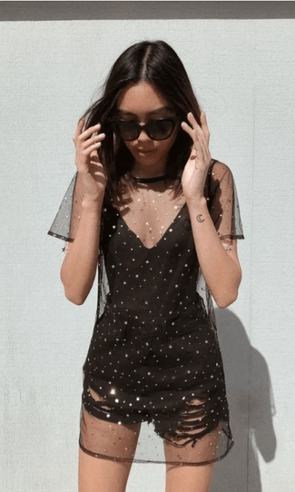Chica con gafas de sol y vestido negro con transparencias de estrellitas