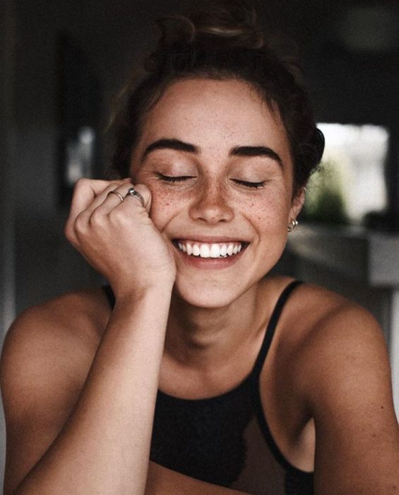 Chica sonriendo con los ojos cerrados