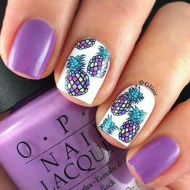 Manicura en tono blanco con morado y decorado de piñas pequeñas