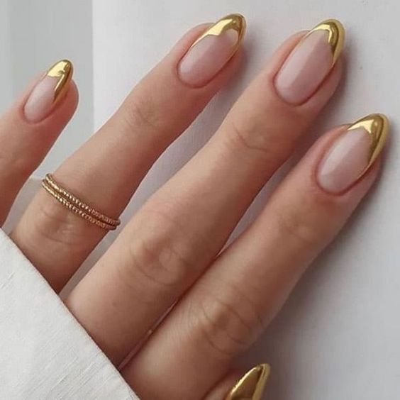 Chica usando unas uñas con tonos dorados brillantes