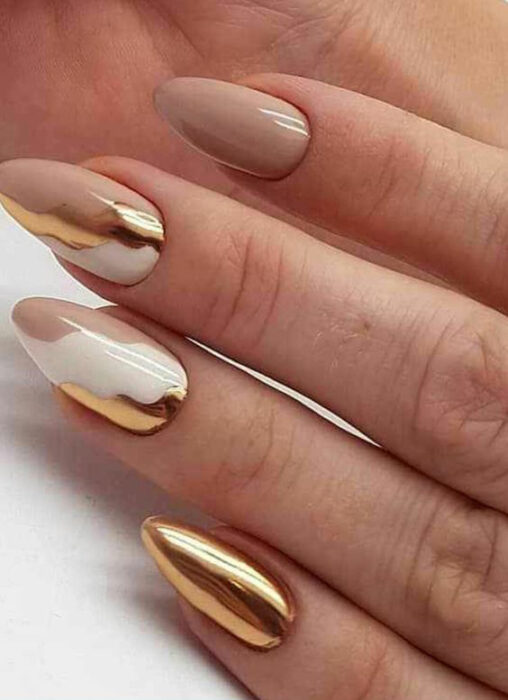 Chica usando unas uñas con tonos dorados brillantes