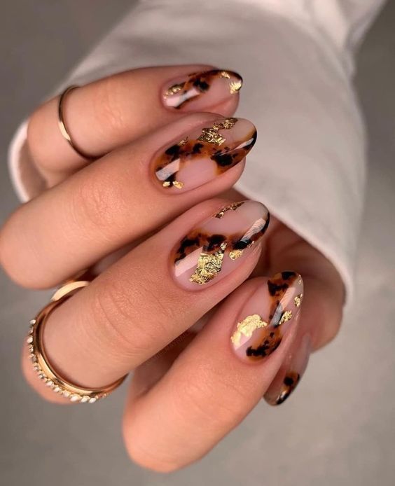 Chica usando unas uñas con tonos dorados brillantes