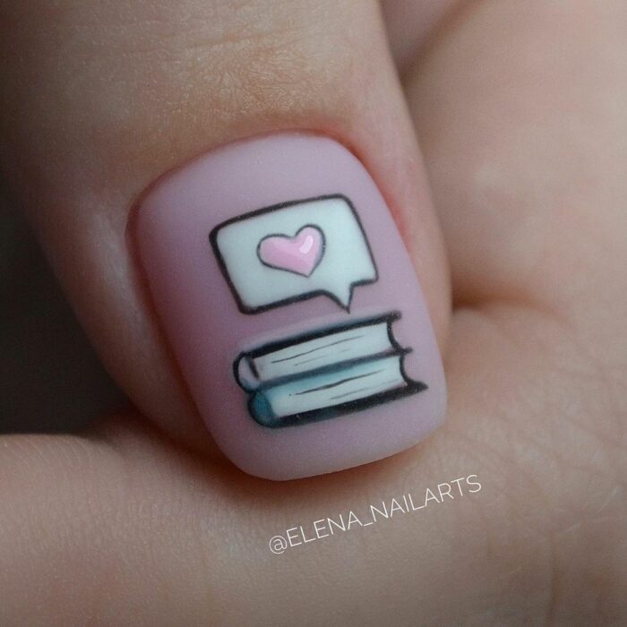 diseño en una uña con unos libros y un corazón