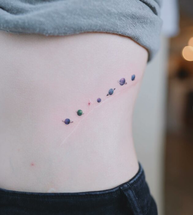 tatuaje de varios planetas de colores en el costado de una mujer
