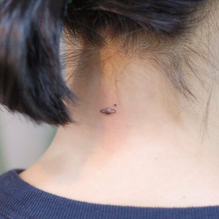 nuca de una mujer con el tatuaje de un planeta
