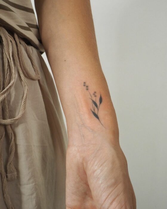 tatuaje de ramas florales en la muñeca de una chica