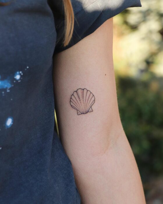 tatuaje de una concha de mar en el brazo de una chica