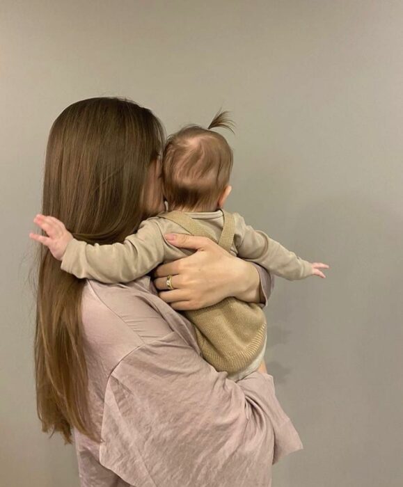 mamá cargando a su bebé, ambas de espaldas