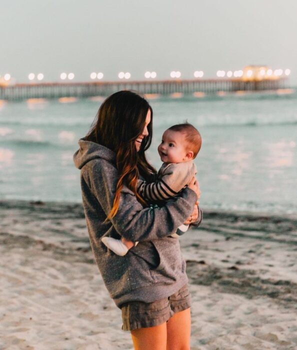 mamá cargando bebé en la playa