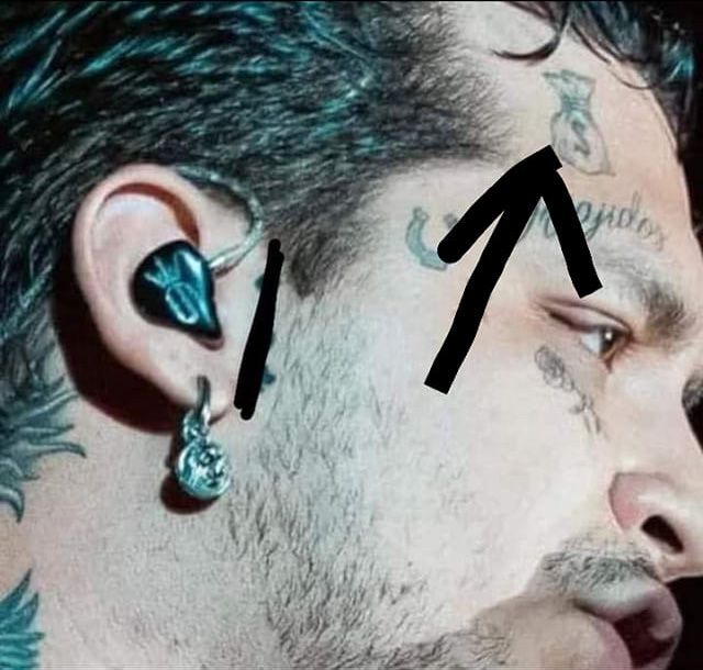 cara de Christian Nodal señalando el signo de pesos en su cara