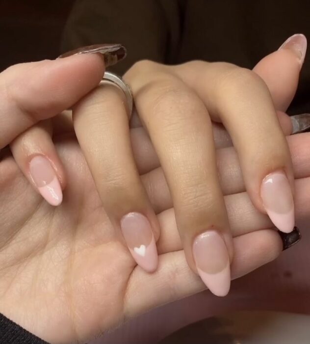 uñas con punta rosa pastel y un pequeño corazón blanco