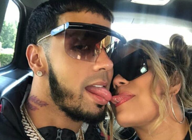 fotografía de los cantantes Karol G y Anuel AA sacando la lengua