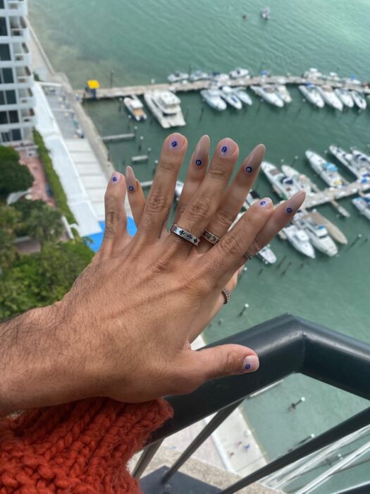 imagen de una pareja con sus manos frente a un balcón en el mar