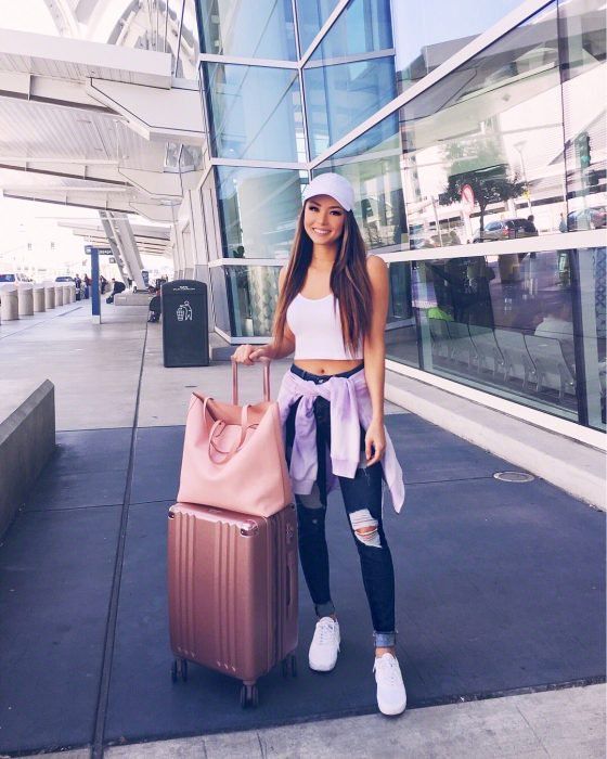 Chica sujetando sus maletas afuera del aeropuerto