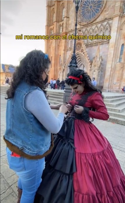foto de una mujer ayudando a su hija a ponerse un vestido negro con rojo