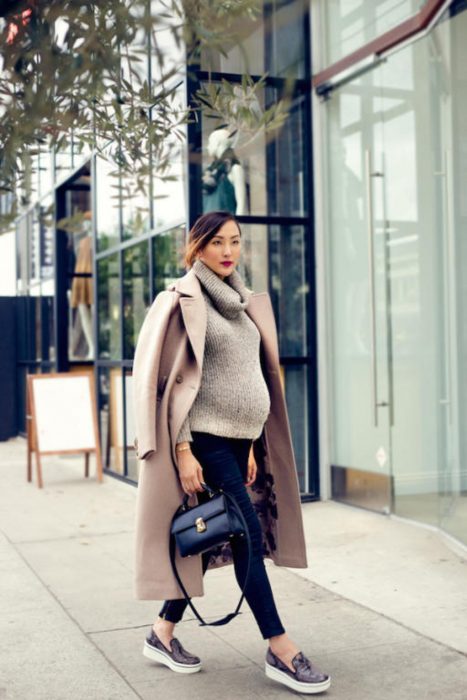 Chica usando un outfit de invierno para presumir con su embarazo