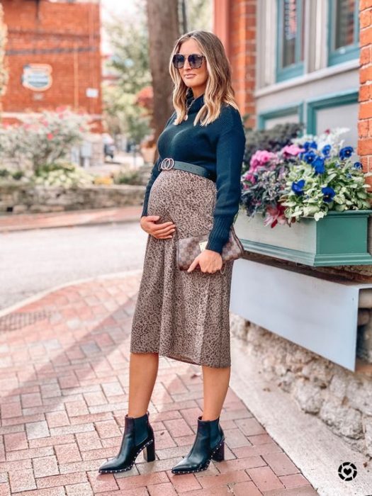 Chica usando un outfit de invierno para presumir con su embarazo
