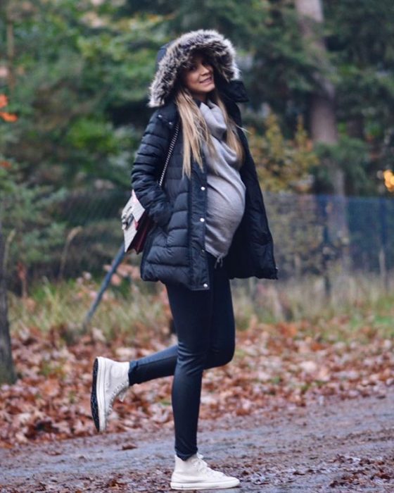 Chica usando un outfit de invierno para presumir con su embarazo