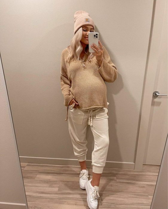 Chica usando un outfit de invierno para presumir con su embarazo