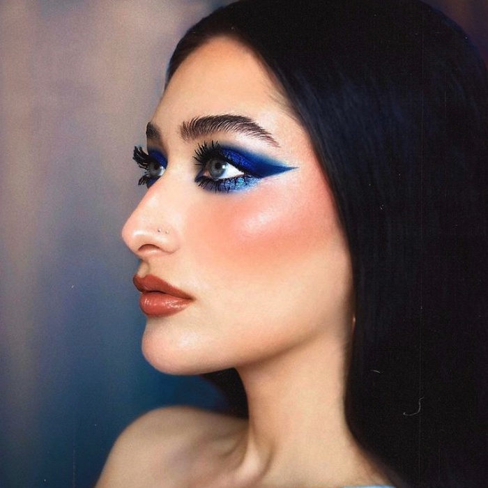 chica con maquillaje, sombras, labial, contour, correcto y pestañas en tonos rosa, azul, rojo y verde para navidad, sombras brillantes, glitter, pestañas postizas, delineado gráfico