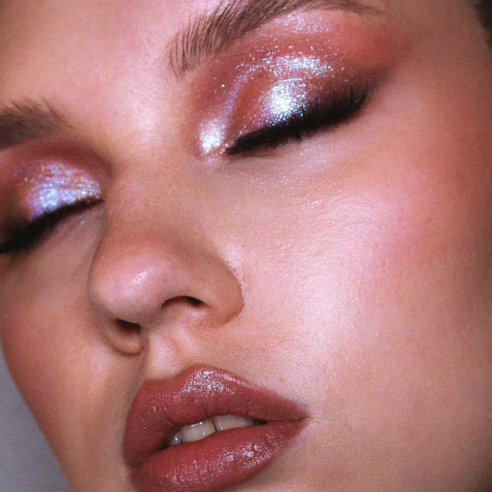 chica con maquillaje, sombras, labial, contour, correcto y pestañas en tonos rosa, azul, rojo y verde para navidad, sombras brillantes, glitter, pestañas postizas, delineado gráfico