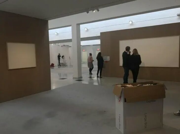 Artista mostrando su obra de dos lienzos vacíos