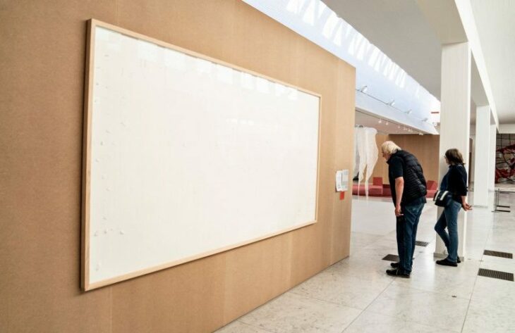 Artista mostrando su obra de dos lienzos vacíos