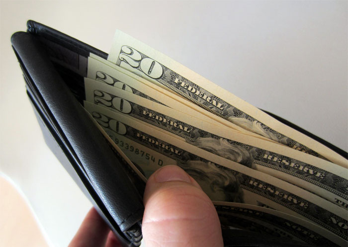 Chica sosteniendo una cartera con dinero 