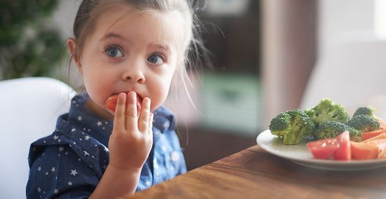 Niña comiendo un platillo con verduras 
