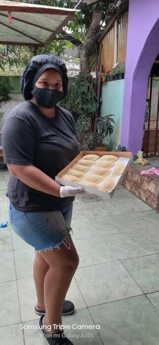 Chica sosteniendo una charola de empanadas; Vende empanadas caseras para cumplir su sueño de ser militar e internet ya salió al rescate