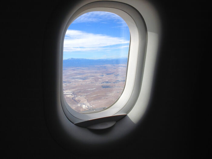 Ventanilla de avión con un paisaje que se ve desde el cielo 