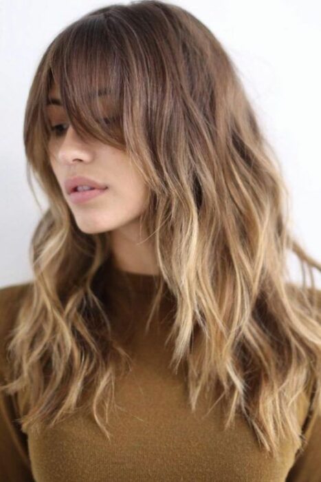 Chica usando un fleco estilo Waft con cabello largo y rubio