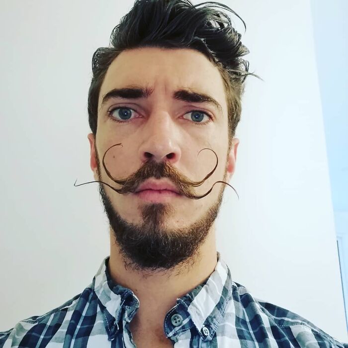 Hombres usando doble bigote en el rostro mientras lo peinan con gracia