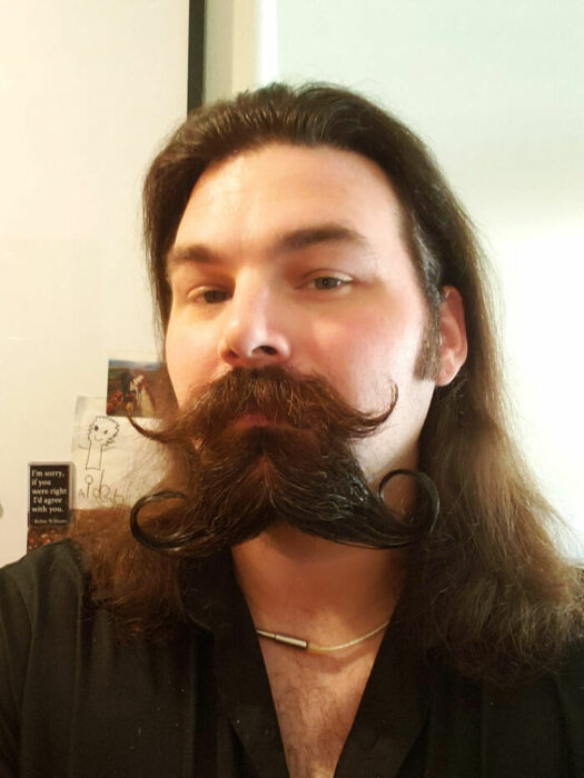 Hombres usando doble bigote en el rostro mientras lo peinan con gracia