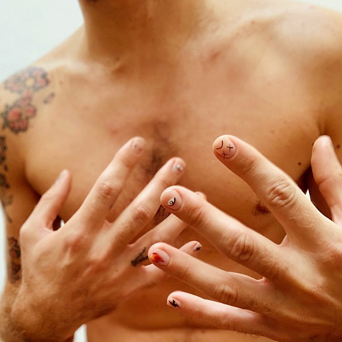 Hombre joven con manicura masculina, estilo moderno en negro, blanco, rojo, amarillo, azul y gris