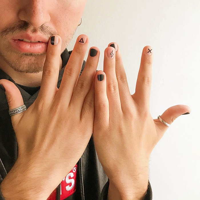 Hombre joven con manicura masculina, estilo moderno en negro, blanco, rojo, amarillo, azul y gris