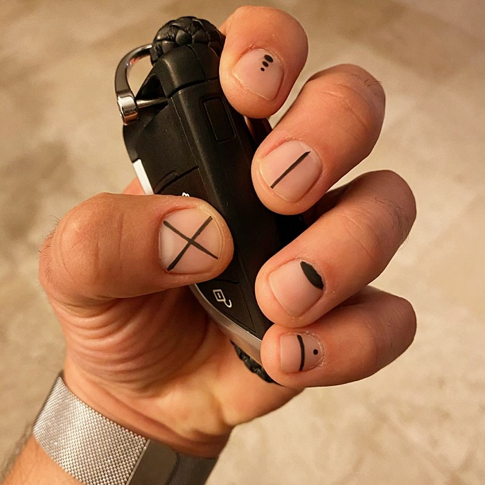 Hombre joven con manicura masculina, estilo moderno en negro, blanco, rojo, amarillo, azul y gris