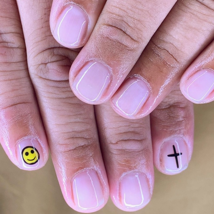 Hombre joven con manicura masculina, estilo moderno en negro, blanco, rojo, amarillo, azul y gris