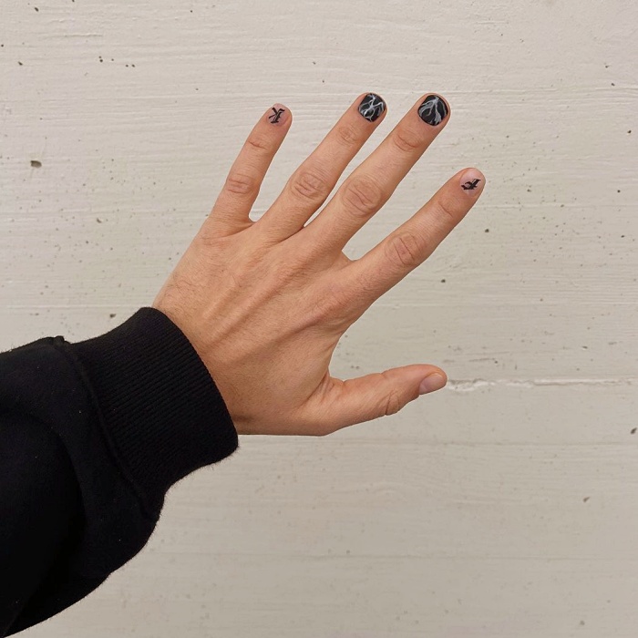 Hombre joven con manicura masculina, estilo moderno en negro, blanco, rojo, amarillo, azul y gris