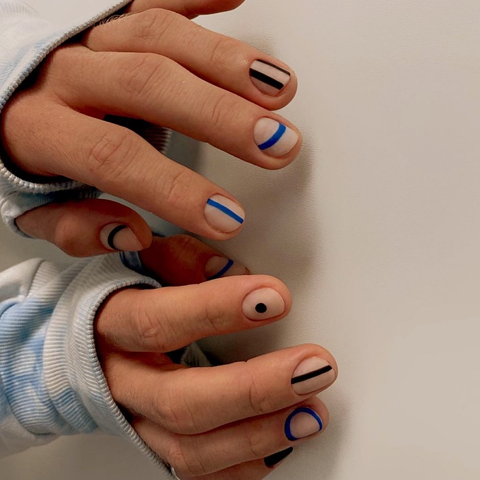 Hombre joven con manicura masculina, estilo moderno en negro, blanco, rojo, amarillo, azul y gris